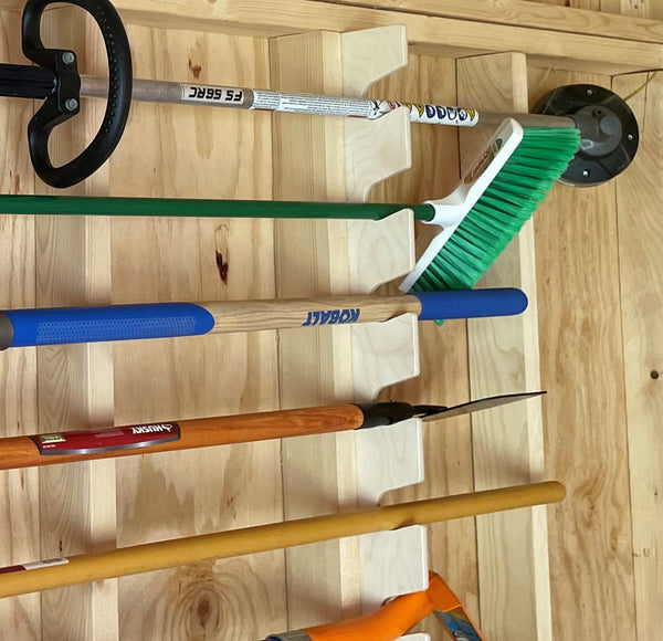 Tool rack for shed storage, featuring a variety of garden and yard tools on a wall mount.
