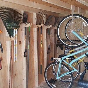 A bike hanging from the ceiling in a shed. Efficient bike storage solution using a wood rack in a yard shed.