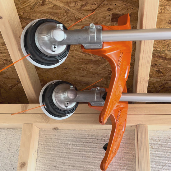 Weed whackers mounted on ceiling in shed.