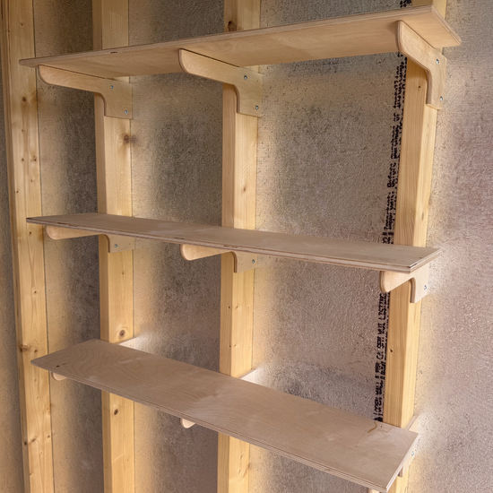 Installing wood shelves on brackets in a shed.