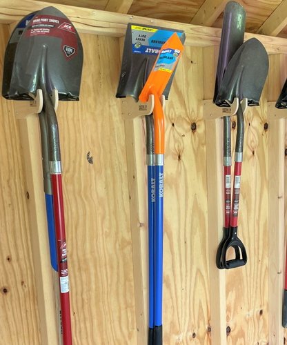 Wall-mounted shed tool rack storing shovels and garden tools securely, maximizing space and keeping equipment organized in a wooden storage shed.