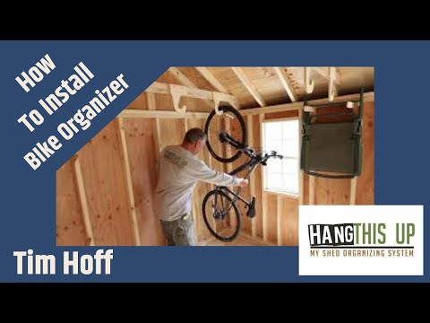 A bike hanging from the ceiling in a shed. Efficient bike storage solution using a wood rack in a yard shed. Video.
